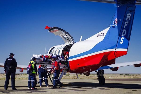 Man attending to patient next to plane